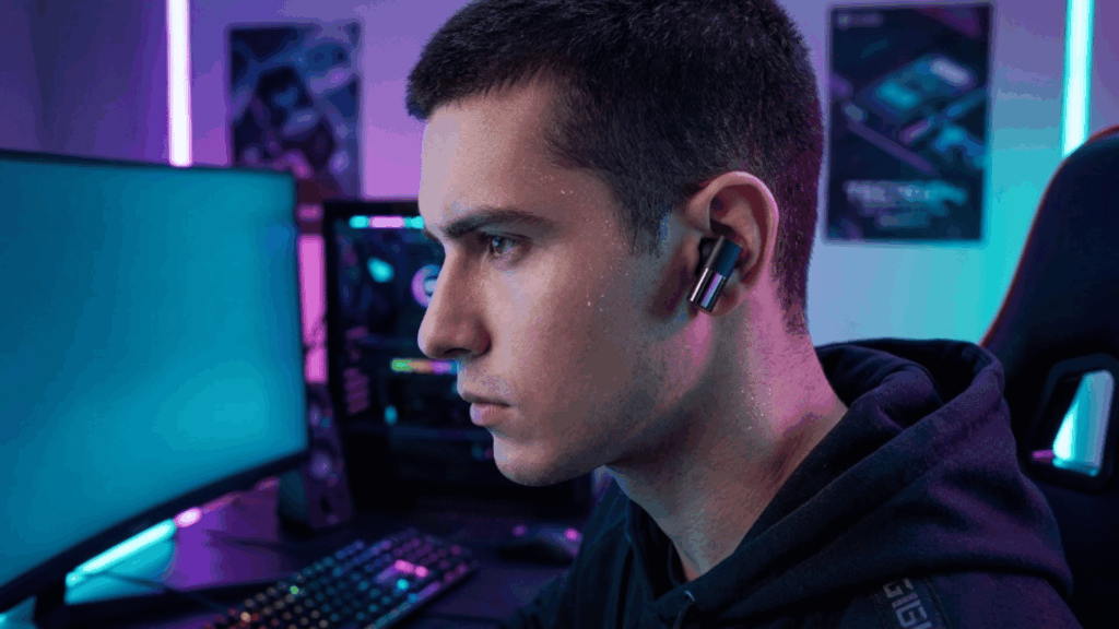 person wearing wireless earbuds while gaming on a PC setup with RGB lighting, showing focus and low-latency audio use