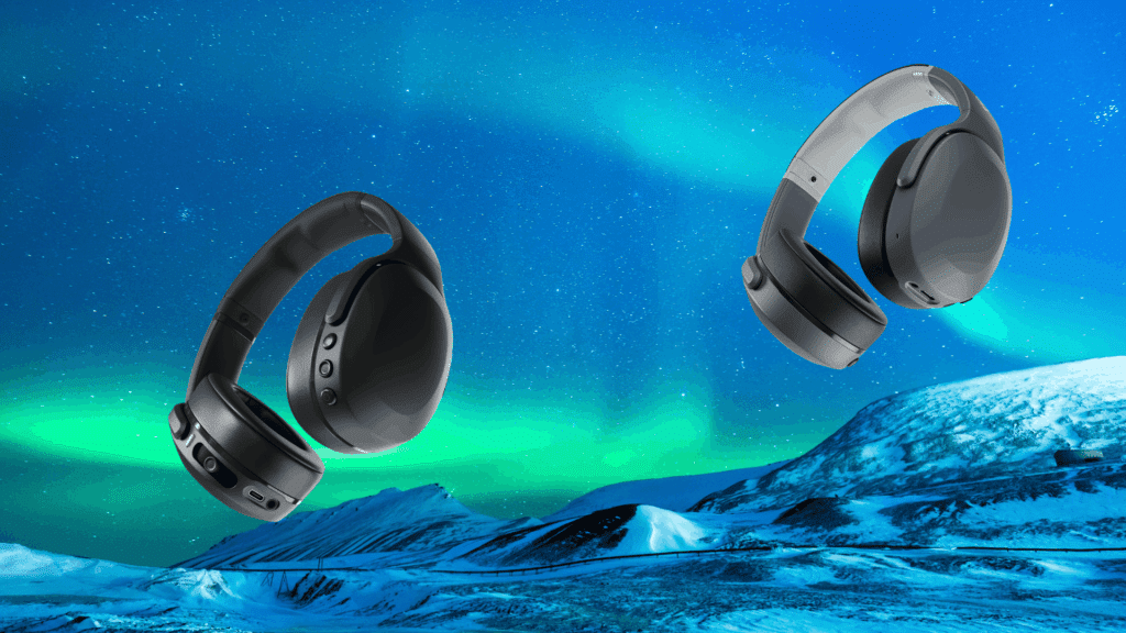 two over-ear wireless headphones in black and gray floating against a blue northern lights sky over snowy mountains.