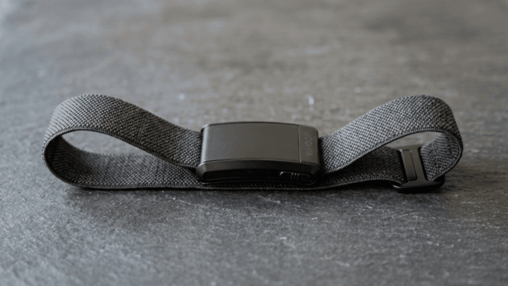 whoop fitness band placed on a flat surface, showing its flexible strap, compact design, and minimal screen-free tracker build