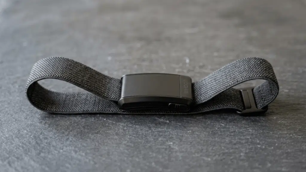 whoop fitness band placed on a flat surface, showing its flexible strap, compact design, and minimal screen-free tracker build