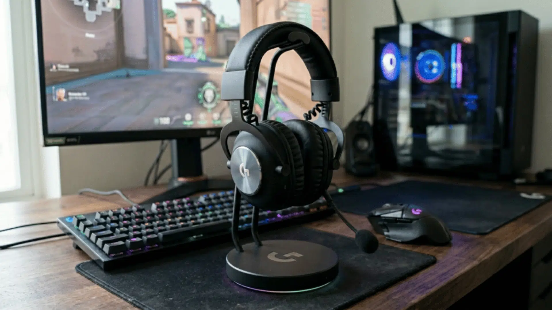 logitech gaming headset on stand with PC setup in background, emphasizing gaming environment and headset design with mic