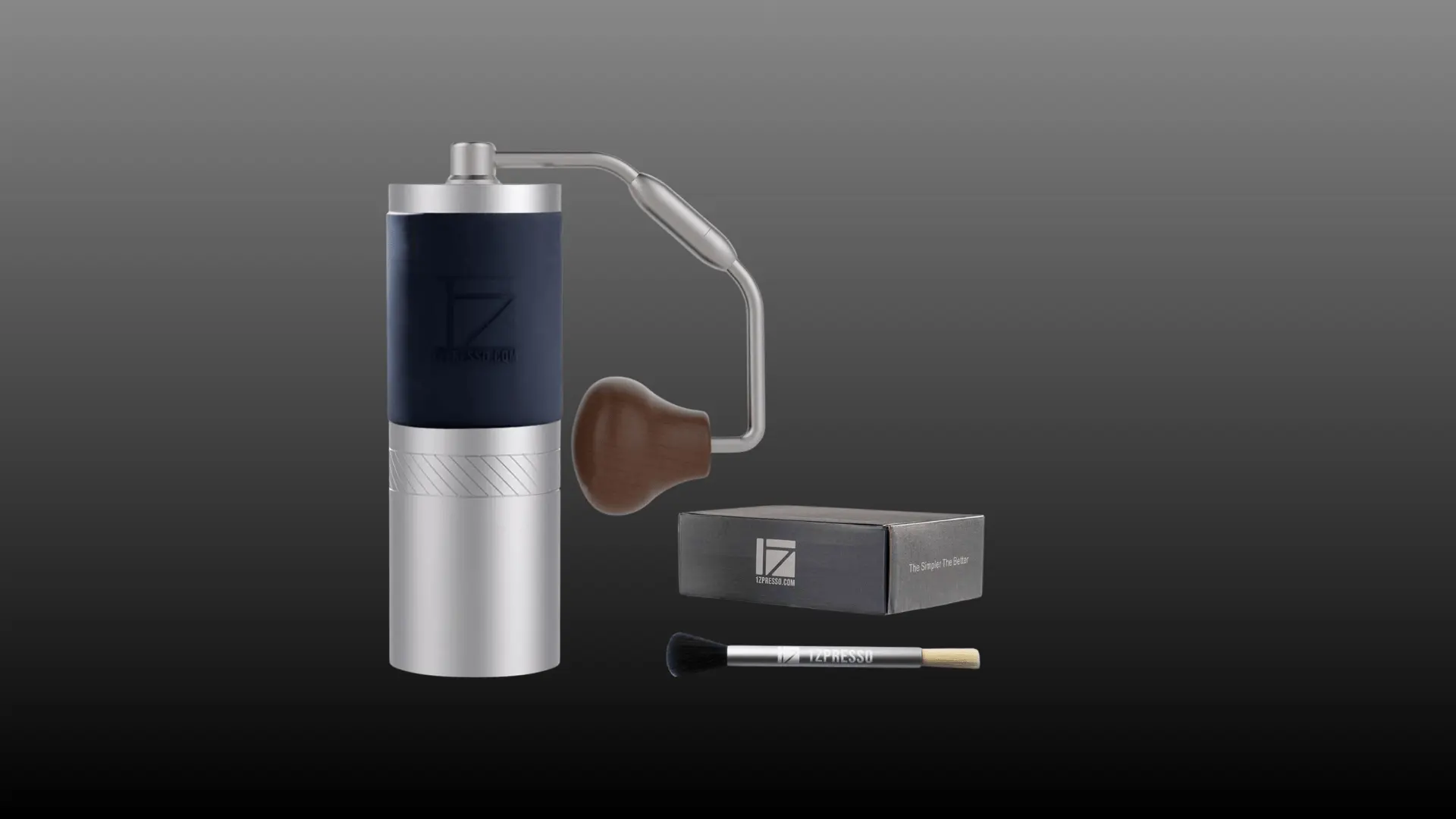 Manual coffee grinder with metal body, side handle, wooden knob, box, and cleaning brush.