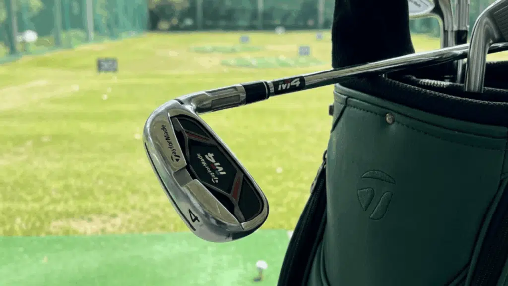 taylorMade M4 iron in golf bag at driving range, showing club design, branding, and clean cavity back look up close