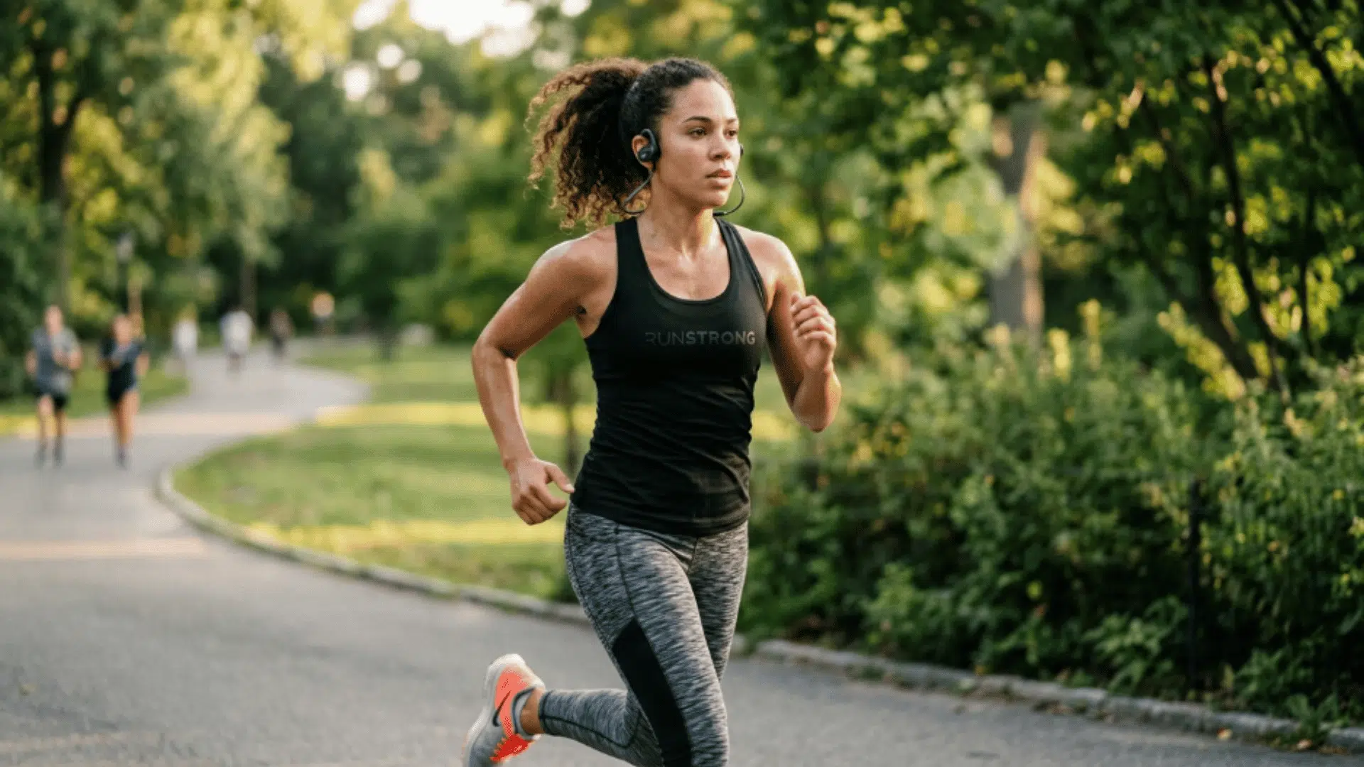 woman running outdoors wearing bone conduction headphones, showing secure fit, comfort, and awareness during workout sessions