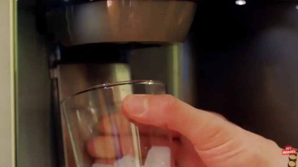 Hand holding a glass under a refrigerator ice and water dispenser
