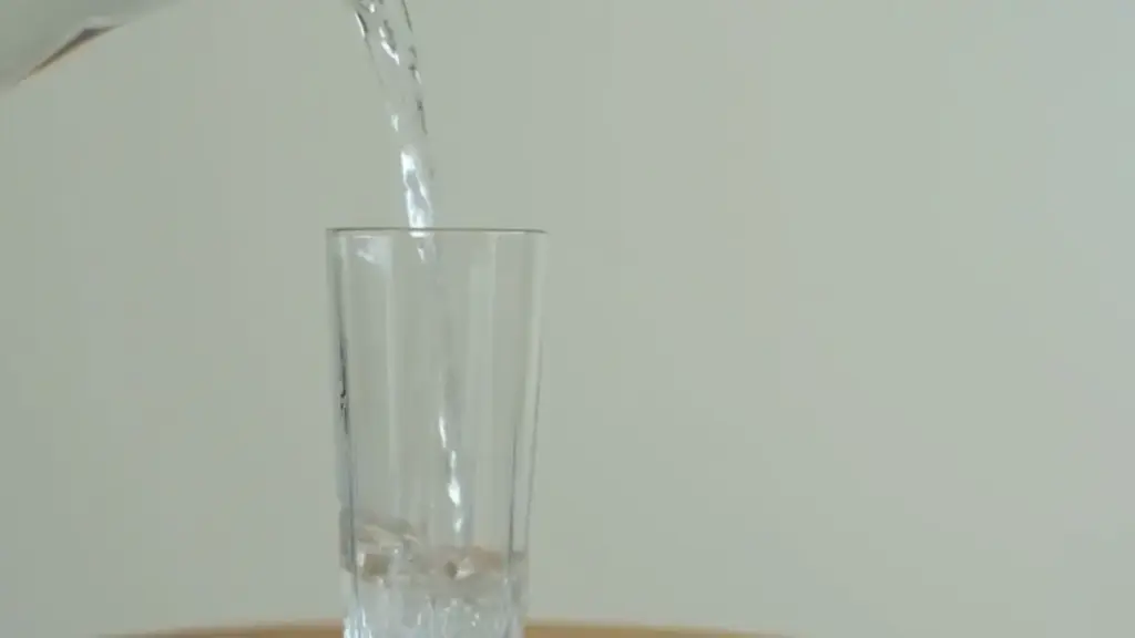 Water being poured into a clear glass from a container