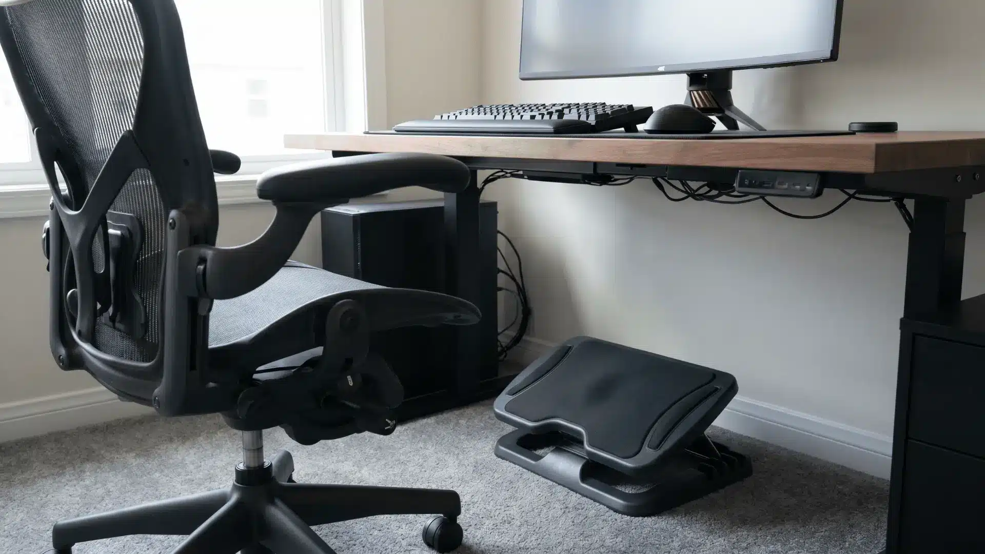 Footrest placed under a desk in front of a chair for proper leg support