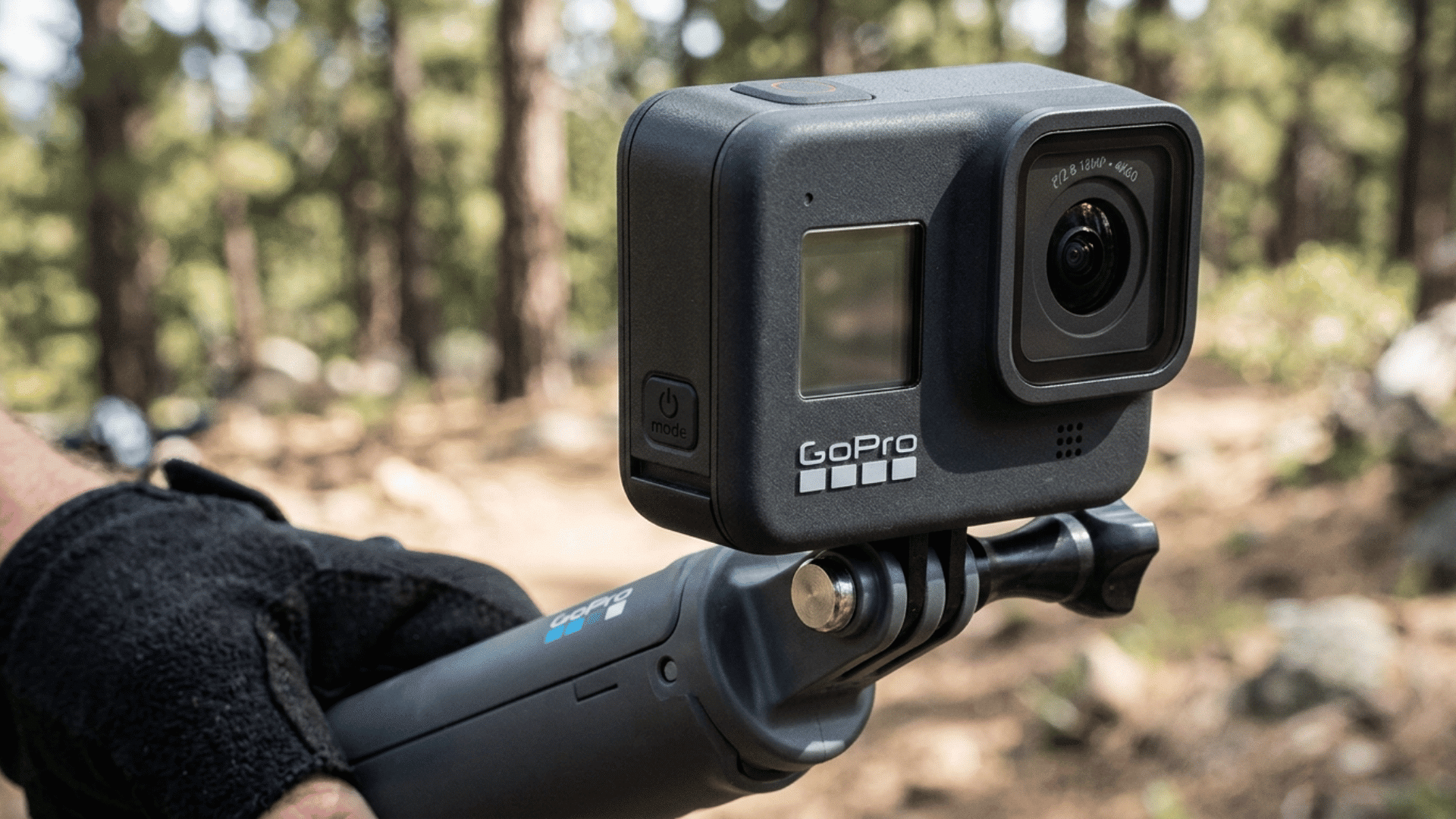 gopro action camera on handheld grip in forest setting, suitable for vlogging, travel videos, and everyday shooting