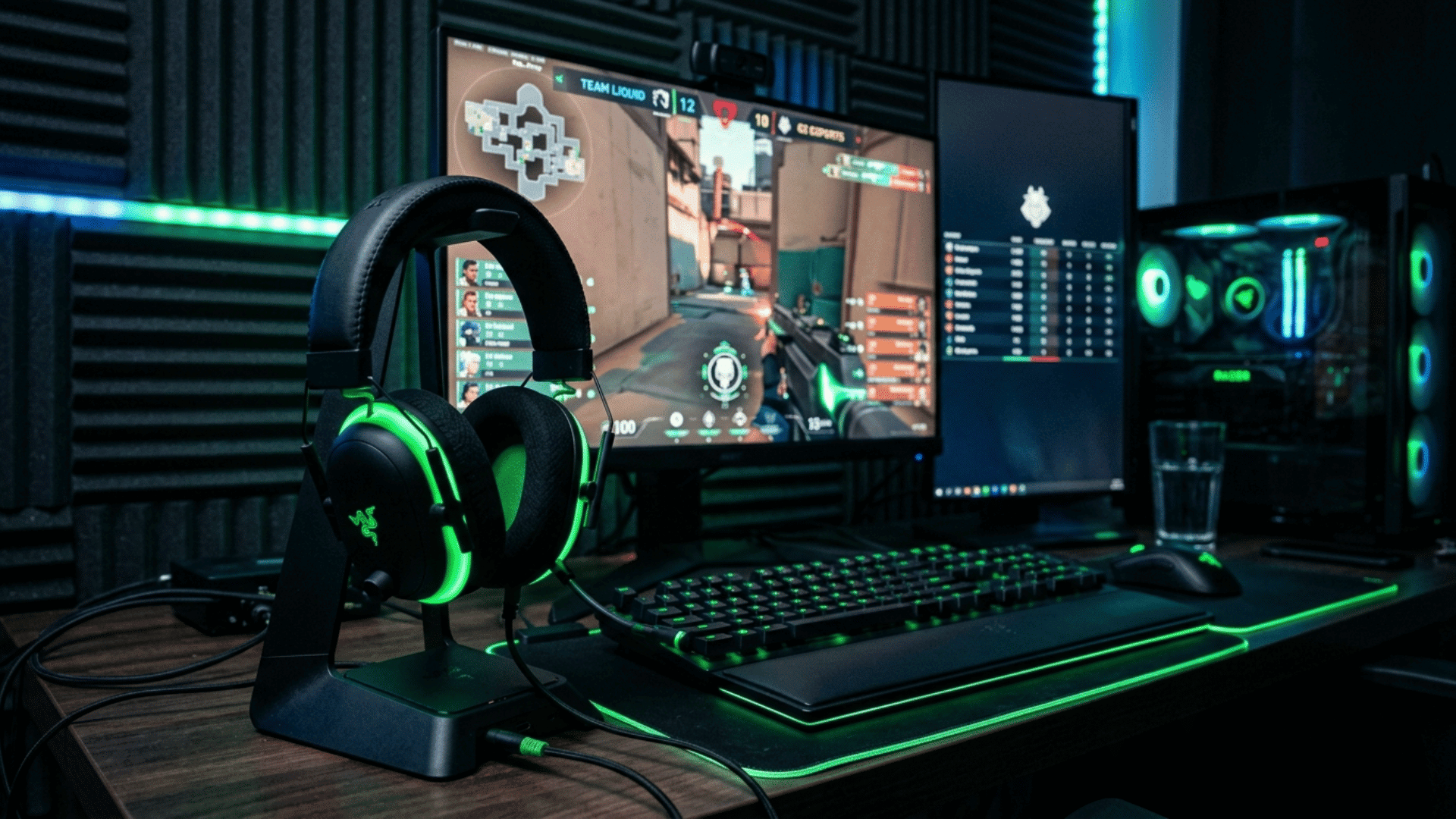 razer gaming headset with RGB lighting placed on desk, dual monitors showing FPS game, focused on competitive gaming setup