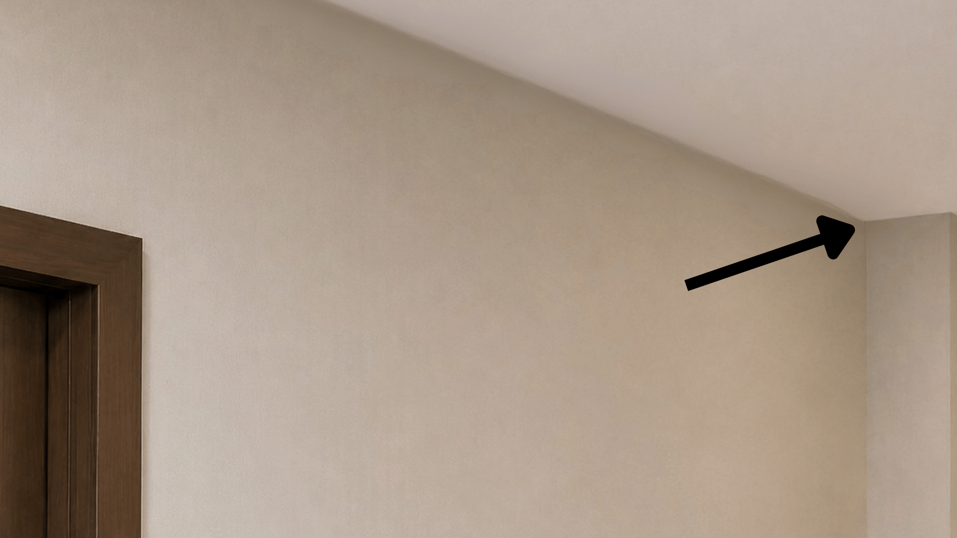 arrow pointing towards the corner of the corridor wall where the cctv camera is to be installed in minimal lighting and off white wall with indoor setting