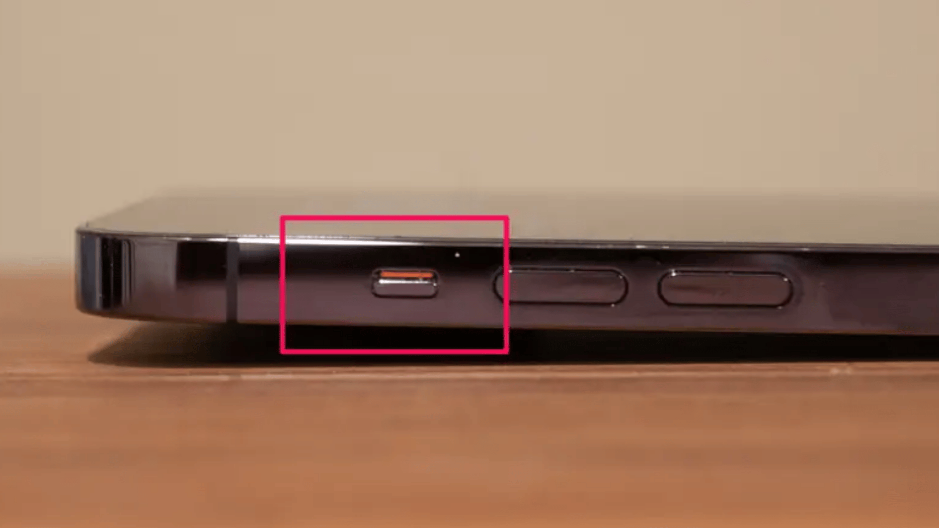 close-up of an iphone side button area showing the ringsilent switch with the orange mark visible, neutral desk background (2)