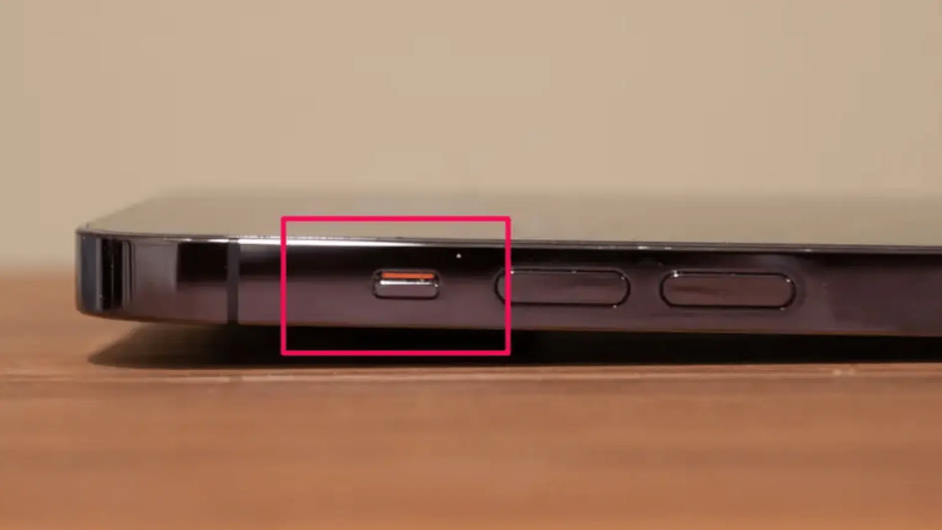 close-up of an iphone side button area showing the ringsilent switch with the orange mark visible, neutral desk background (2)