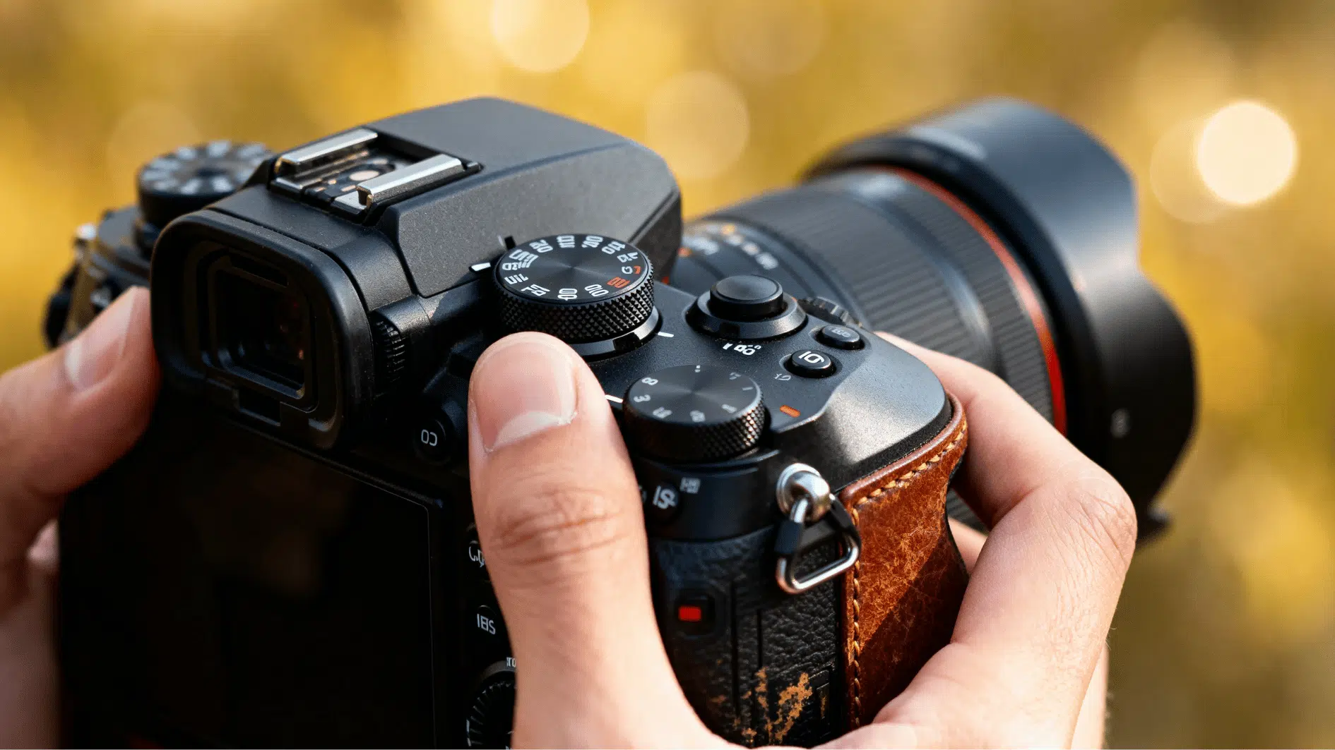 close-up of hands adjusting manual controls on a dslr camera with a blurred outdoor background and warm lighting.