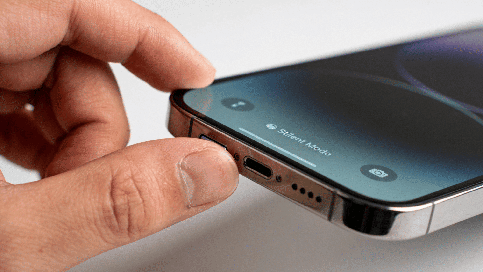 hand switching iphone to silent mode using the side button with silent mode shown on the screen display