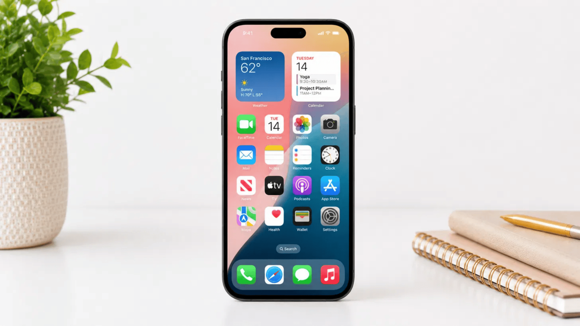 iphone home screen showing settings app icon on white desk with plant and notebook