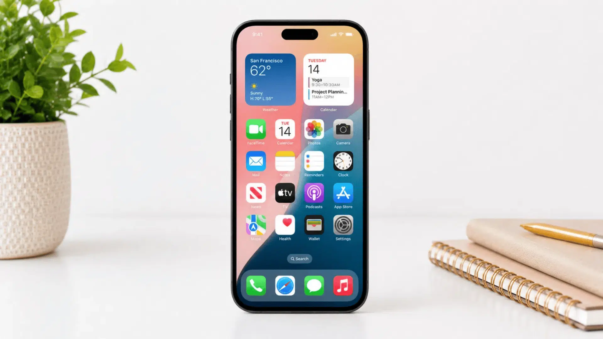 iphone home screen showing settings app icon on white desk with plant and notebook