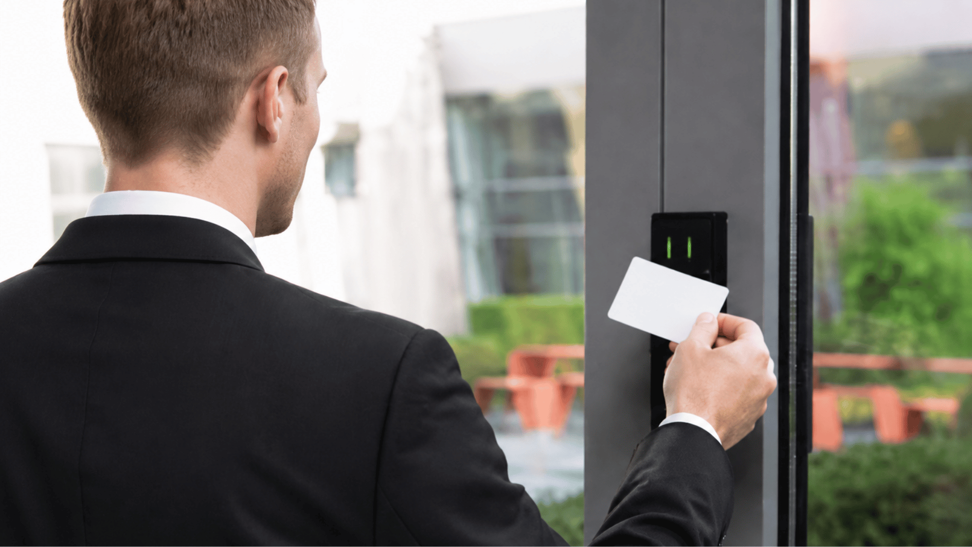 man in a black suit uses a blank white access card at a secure door entry reader