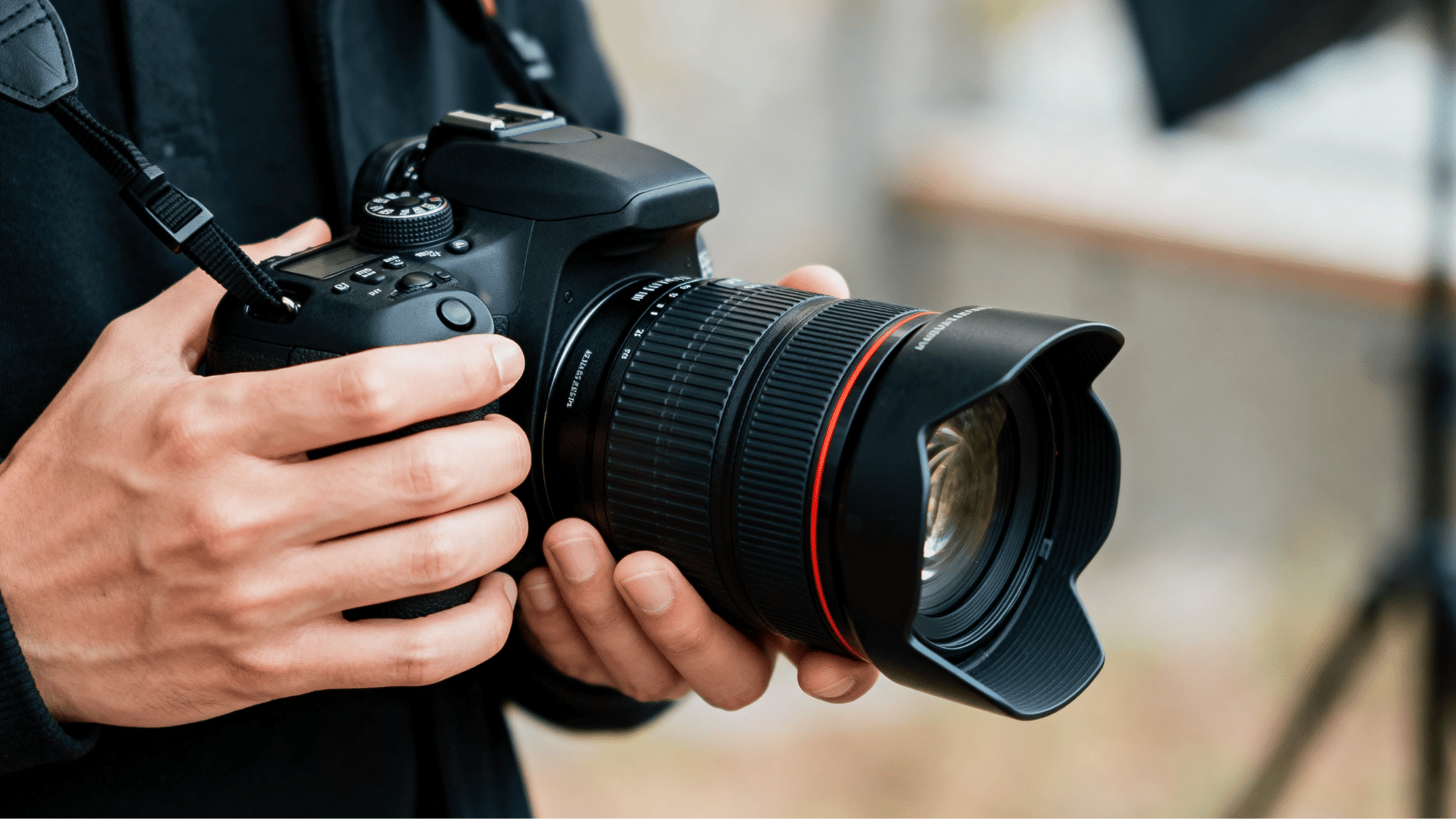 person comfortably holding a dslr camera with a large lens during an outdoor photography session with soft background blur.