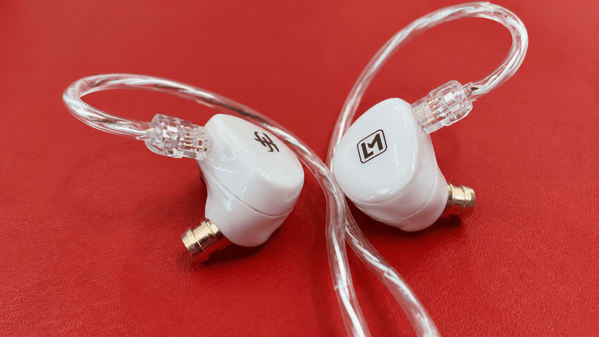 simgot ea500lm wired earphones kept on a red textured table with simgot logo visible on the surface of buds with golden color nozzles and white color body