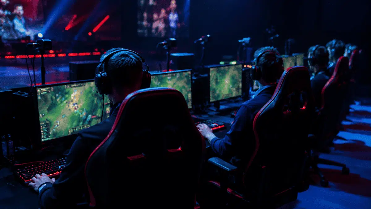 group of esports gamers wearing headsets sitting together at computer setup during competitive gaming match