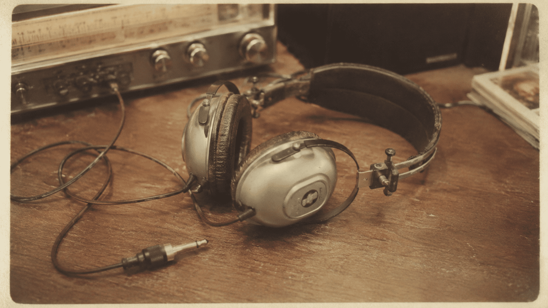 stereo headphones from the 1960s beside a vintage receiver in a faded archival-style photograph