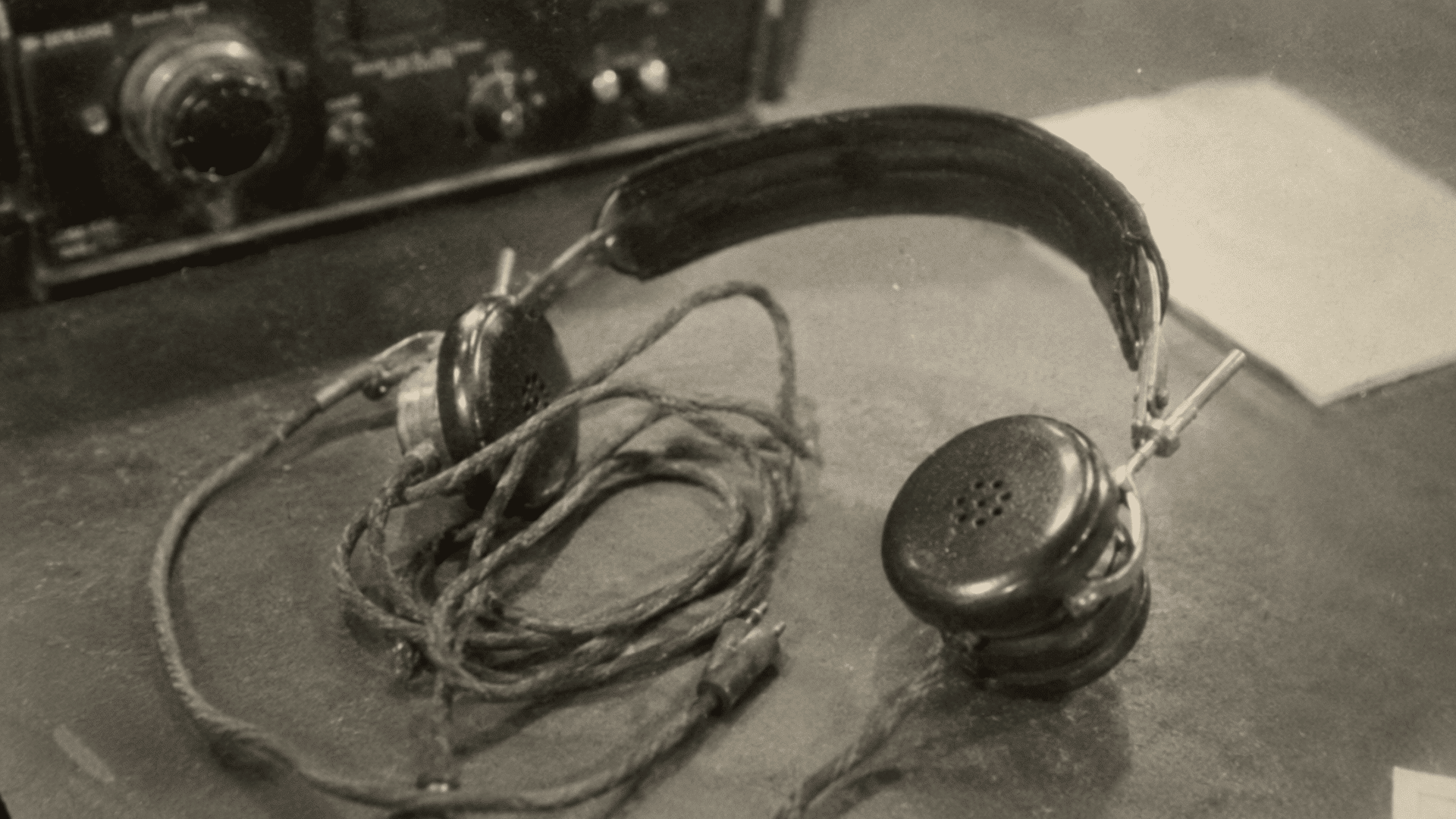 vintage radio communication headphones from the 1930s on a desk in a grainy black and white archival photo