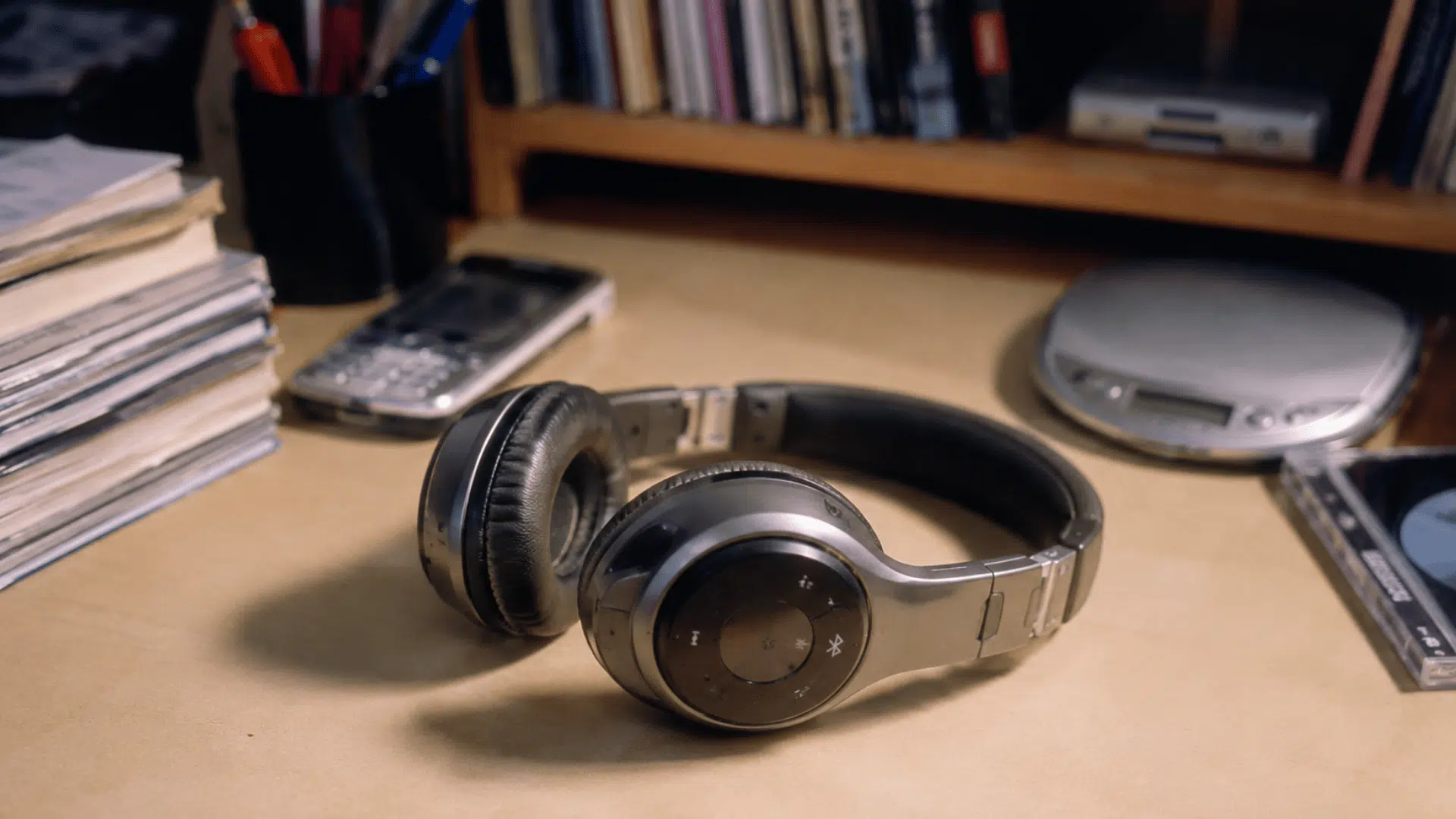 wireless bluetooth headphones from the 2000s on a desk with cds and early digital devices