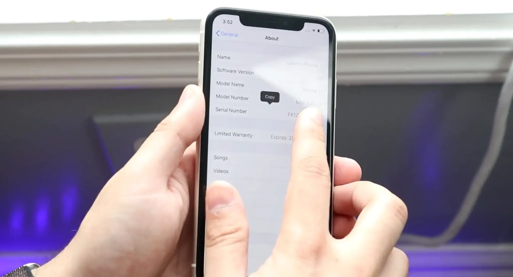 Person copying an iPhone serial number from the About screen in Settings.