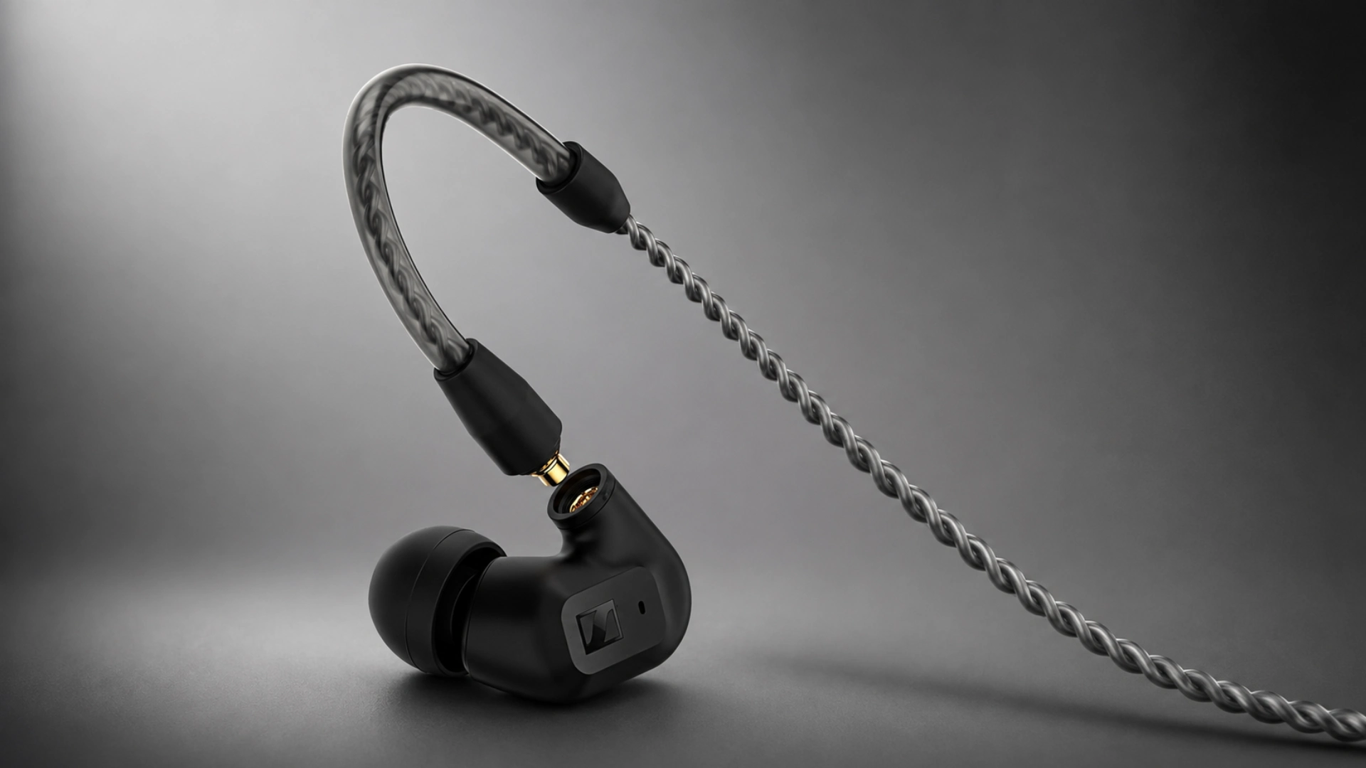 Black detachable earbud and braided cable displayed on a dark gray studio background