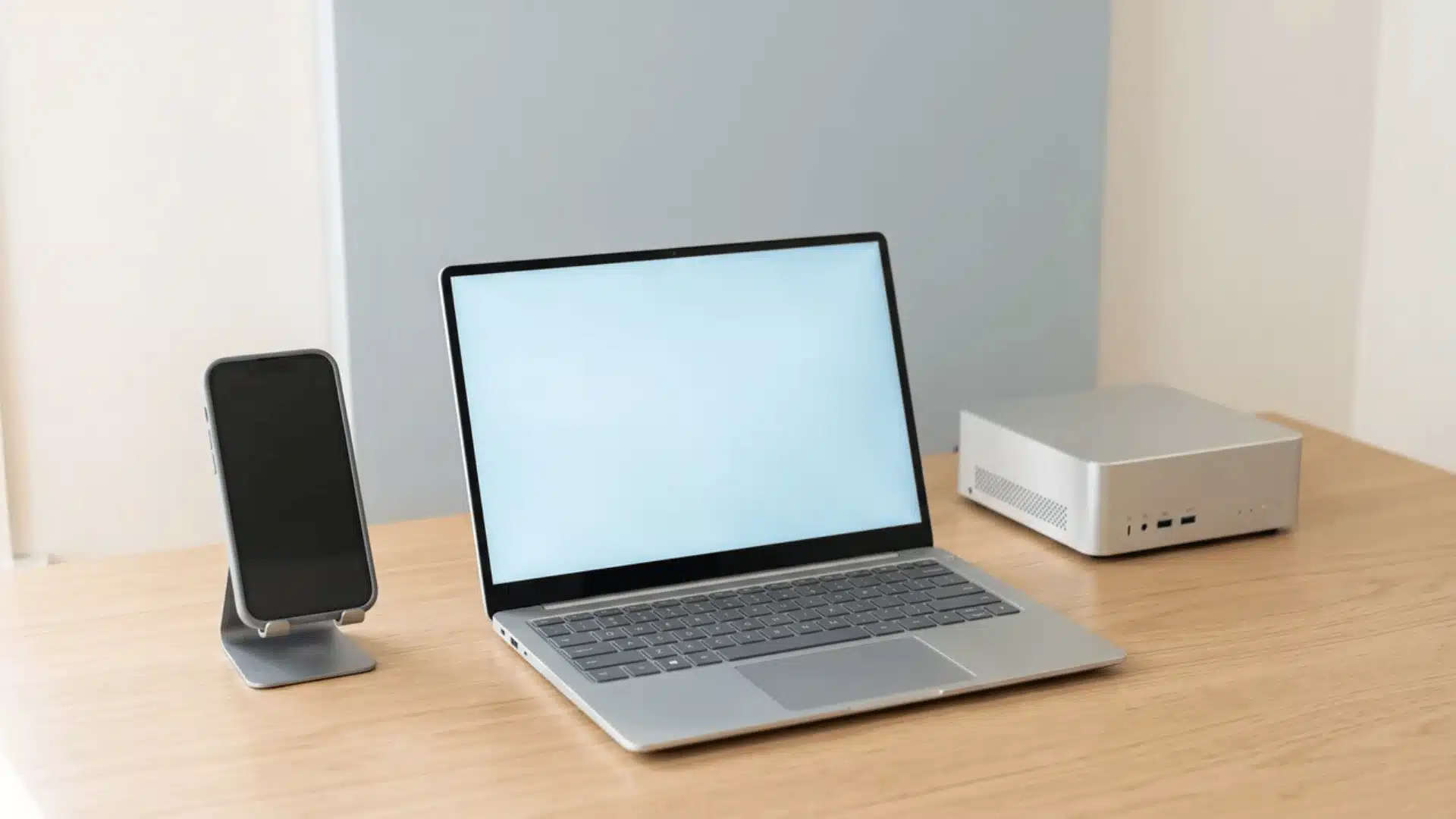 PC laptop with a smartphone and compact desktop relay computer on a light wood desk