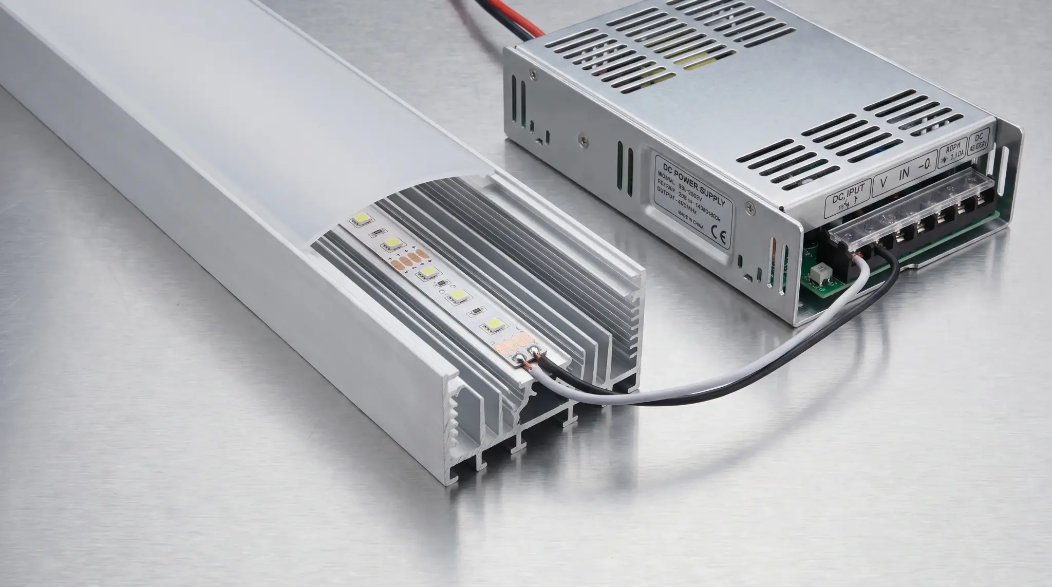 LED strip mounted in an aluminum channel beside its connected power supply