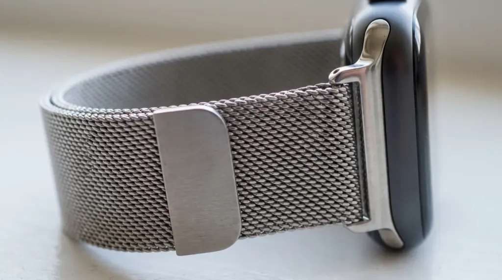 Metal mesh smartwatch band with magnetic tab threaded through its adjustment slot