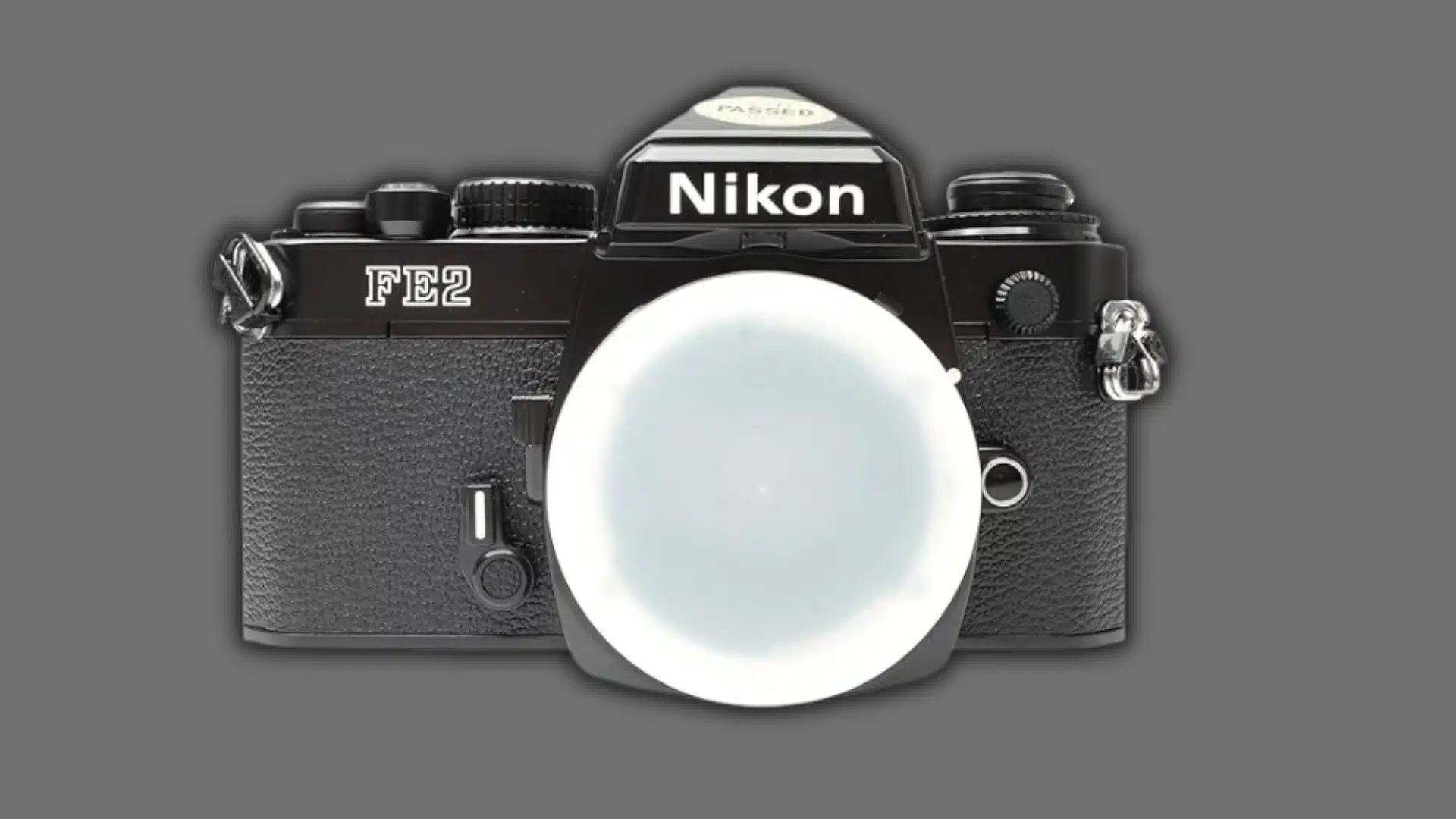 Front view of a black Nikon FE2 film camera body with a white body cap on a white background.