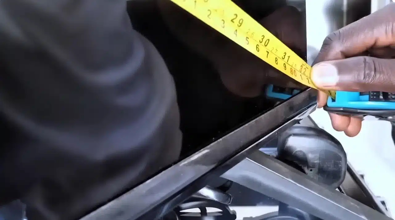 Close-up of a tape measure showing the diagonal TV screen measurement at the bottom corner.