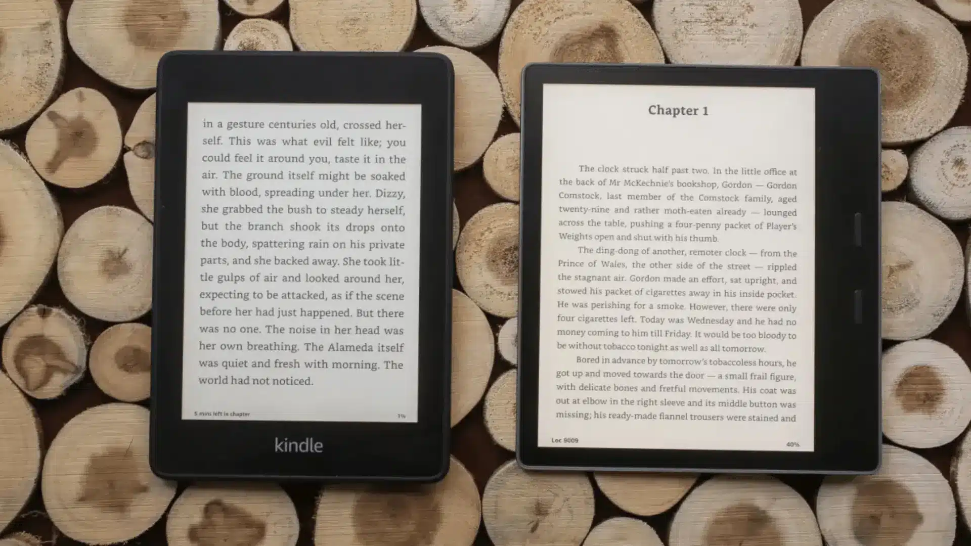 Two black e-readers displaying book pages side by side on stacked cut wood logs