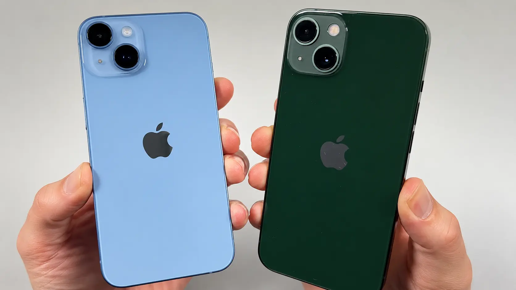 Two iPhones in light blue and dark green held side by side, showing their rear cameras and Apple logos