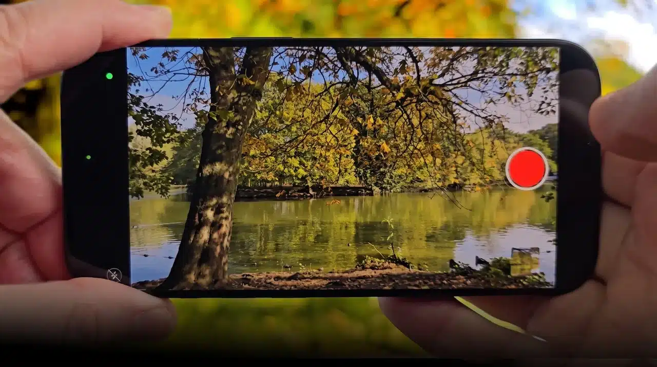 Hand holding phone recording 4K video of a lake and trees outdoors