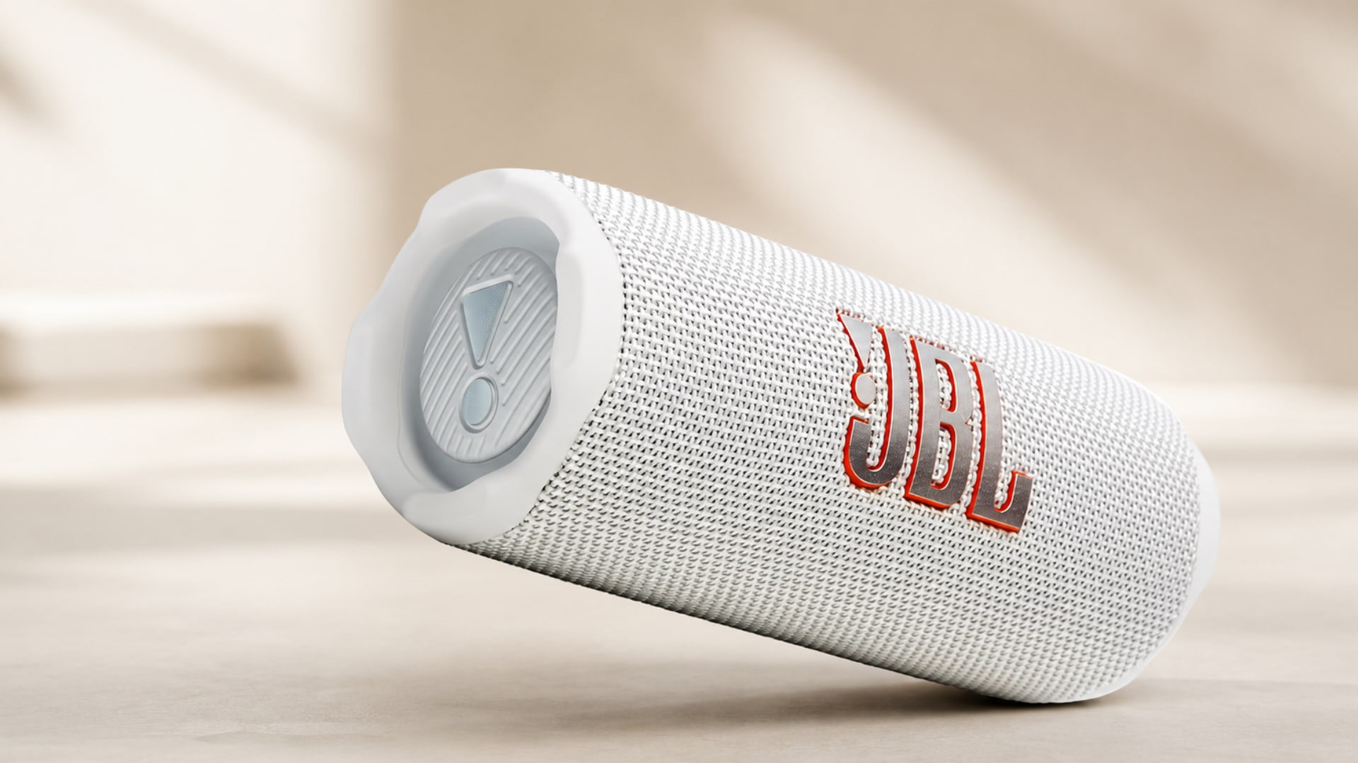 White JBL Flip 7 speaker displayed on a soft beige studio surface with warm lighting