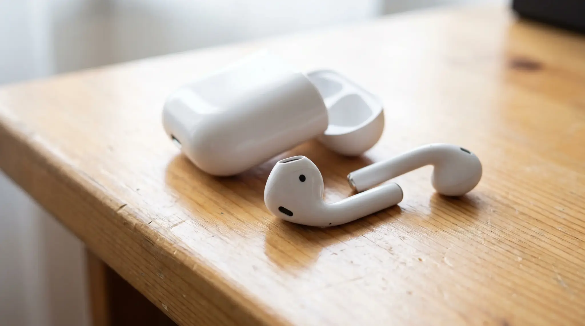 Wireless earbuds with visible ear-detection sensors beside an open charging case.