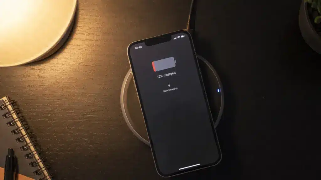 iPhone 14 on a wireless pad displaying a stalled charging screen with low battery icon